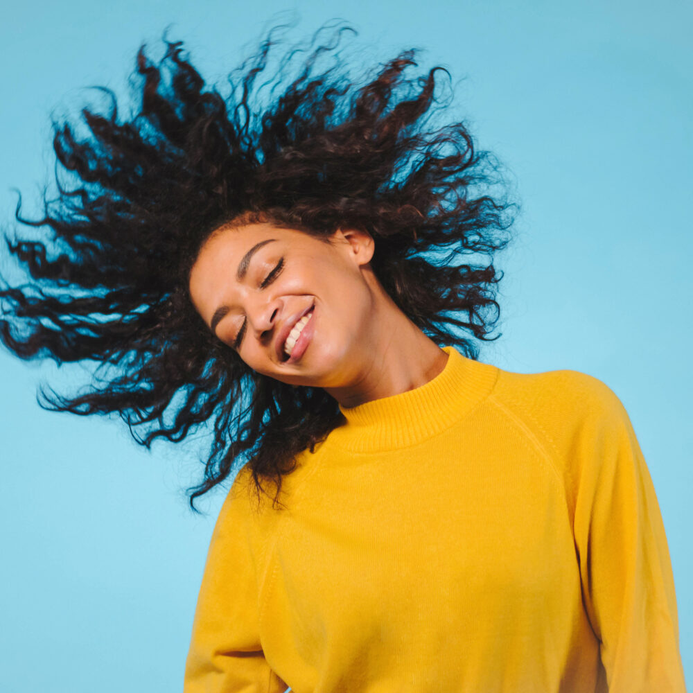 happy-young-woman-with-tousled-hair-against-blue-background